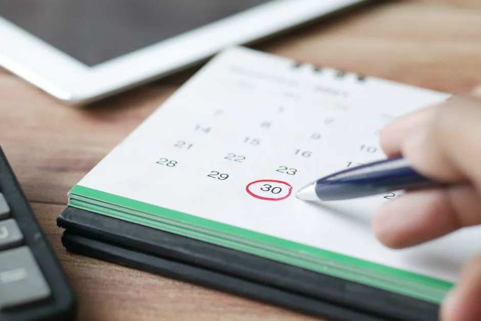 Main marquant une date sur un calendrier pour planification des rendez-vous